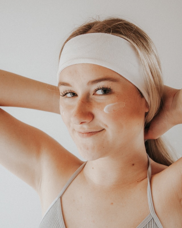 Ragazza che applica la crema viso