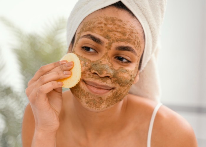 ragazza che toglie scrub viso dal viso con spugnetta